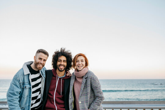 Three friends together by the sea at dusk